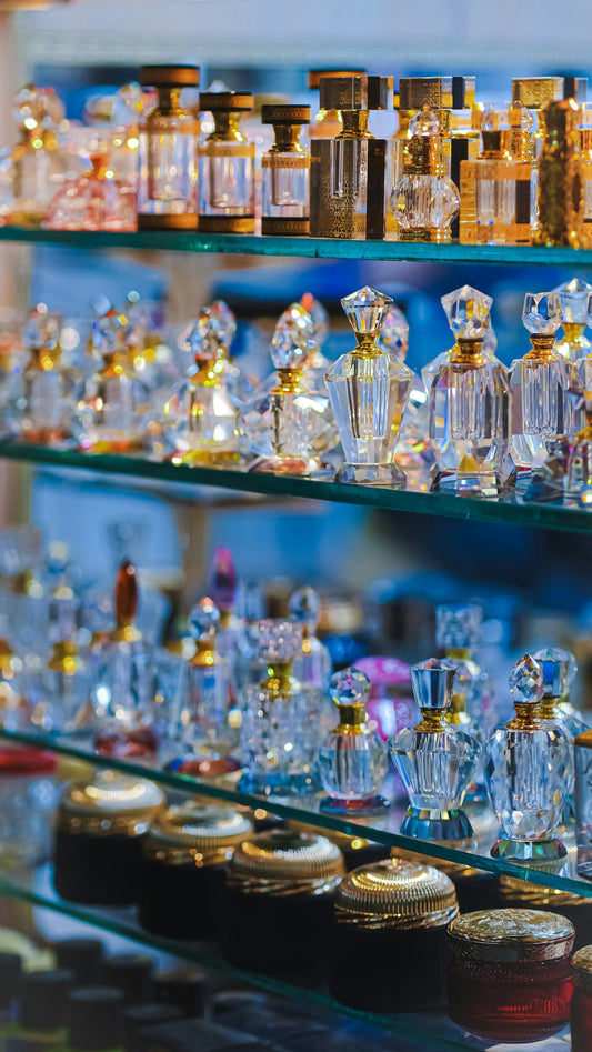Collection de flacons de parfum en verre décoratif avec bouchons dorés, exposés en vitrine.